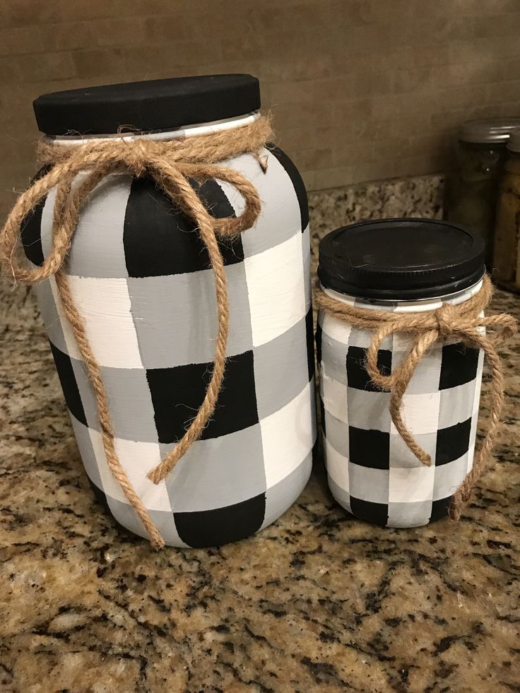 two black and white checkered jars are sitting on a granite counter with twine rope