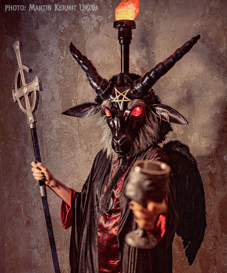 a demon with horns and devilish makeup holding a hammer