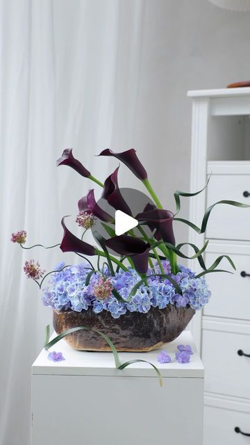 a vase filled with purple flowers on top of a white table