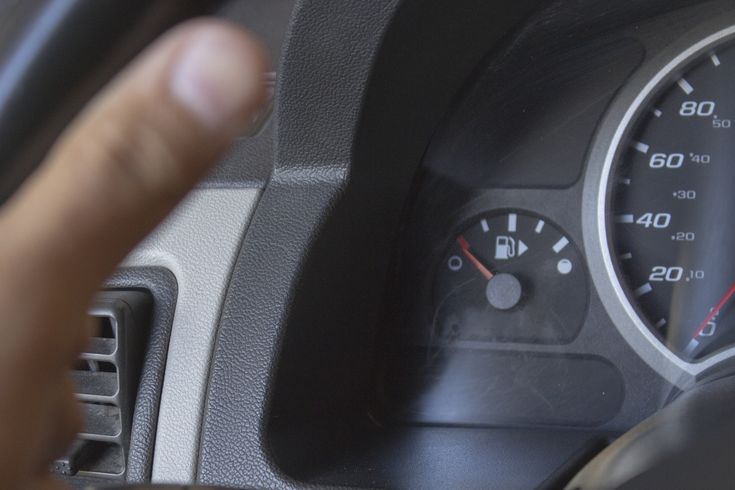 a close up of a speedometer on a car's dashboard with someone pointing at it