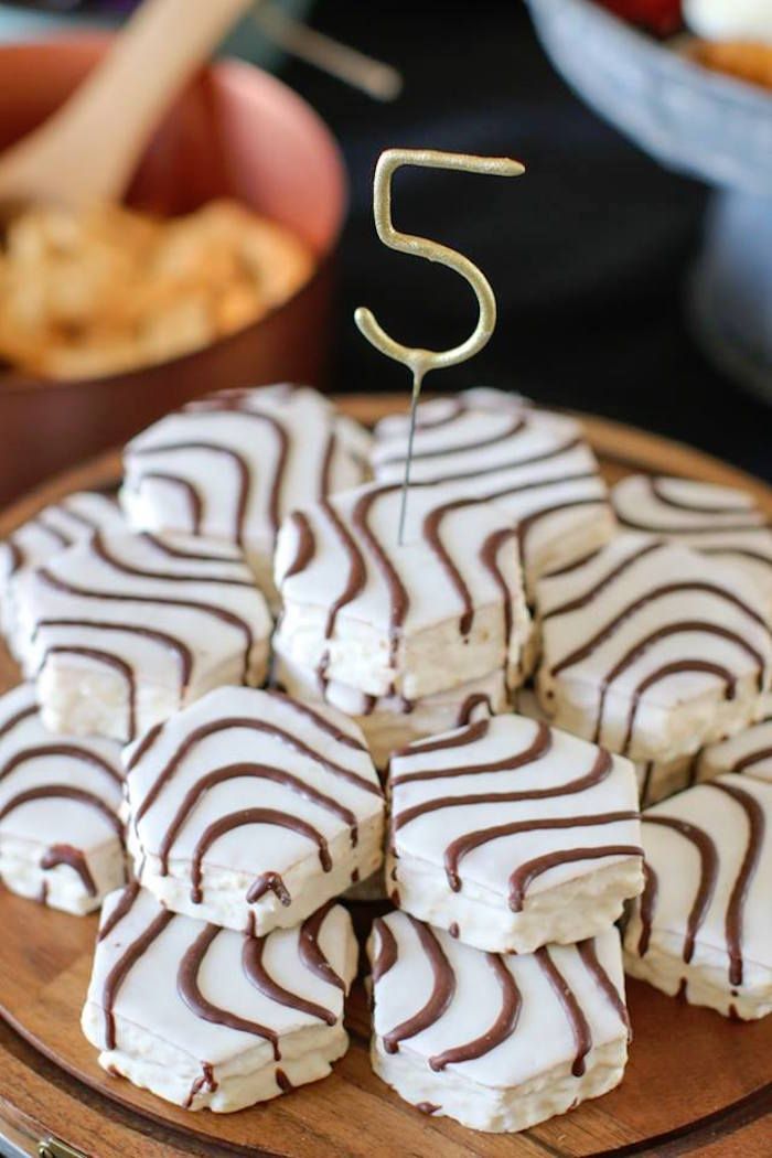 a wooden plate topped with white and brown desserts