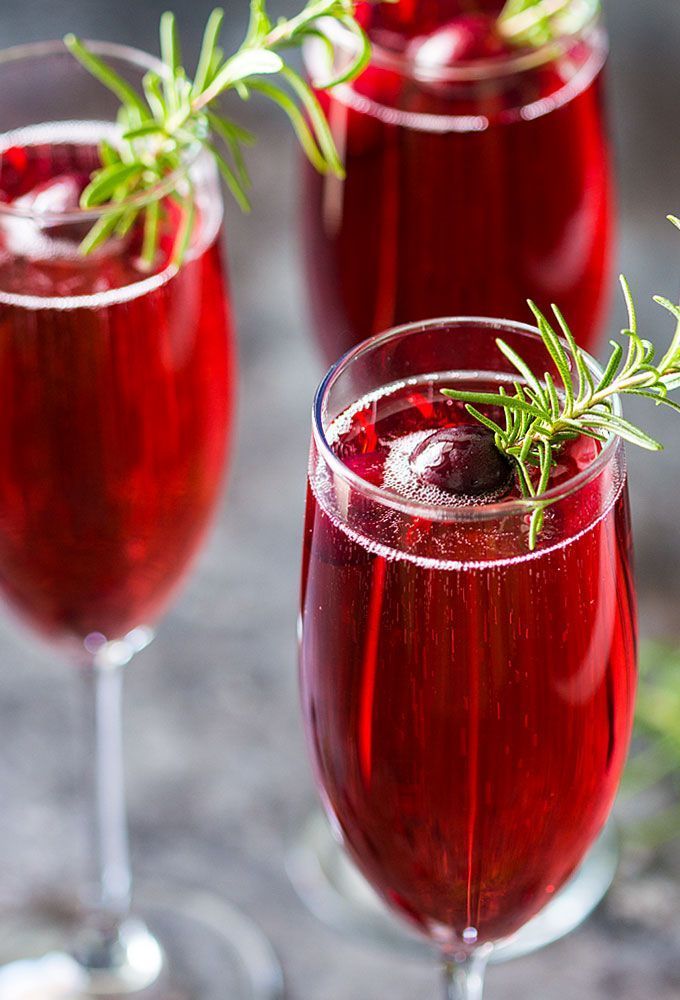 three glasses filled with red wine and garnished with rosemary