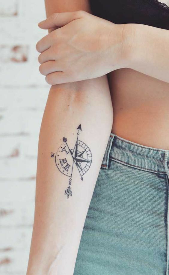 a woman's arm with a tattoo on it that has an arrow and compass