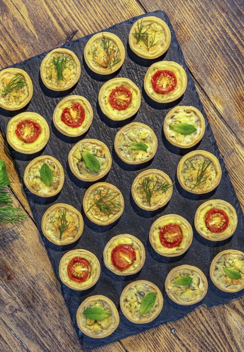 an assortment of appetizers are displayed on a black cloth with green and red designs