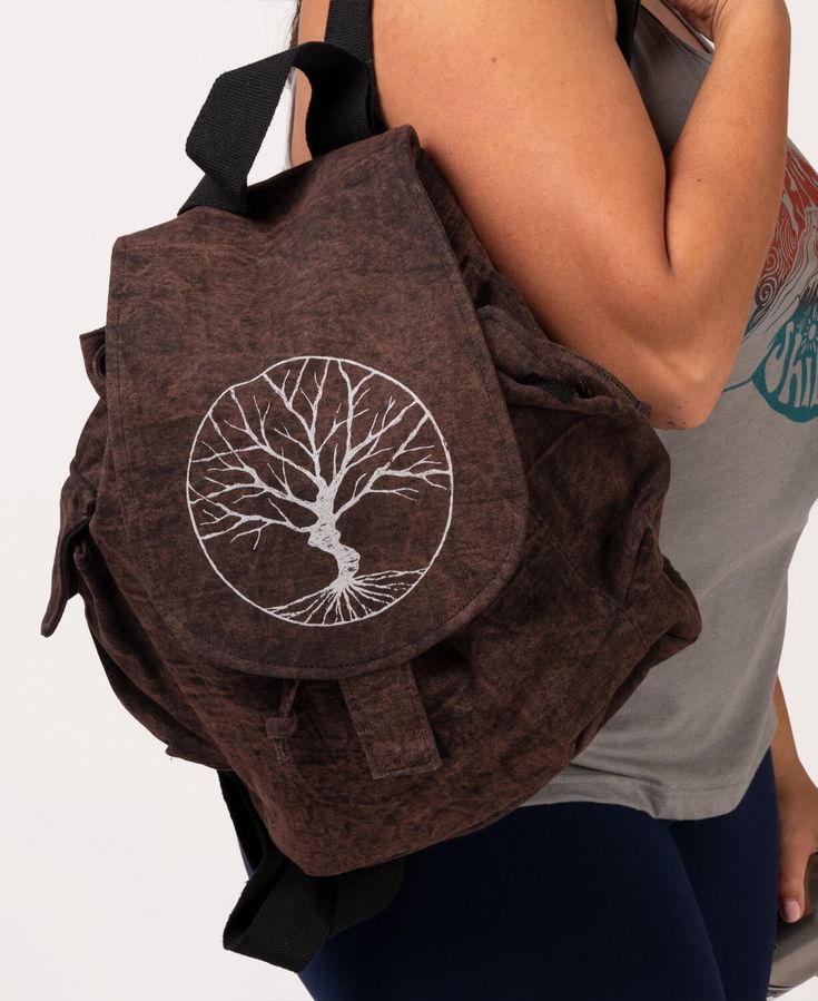 This Sketchy Tree Slouchy Backpack will keep you connected to all of nature's beauties. Wear it on your travels to the farmer's market, eco-friendly shops, or your favorite nature spots. Features a sacred tree symbol hand screen-printed on a heavy cotton canvas bag. Created with hook and loop flap side pockets and plenty of room in the main pouch and side cargo pockets to carry your things. Includes a cinch tie with a hook and loop flap for closure.  14 x 12 x 4.25 inches with 19-35 inch adjusta Eco-friendly Outdoor Backpack, Eco-friendly Backpack For Outdoor, Eco-friendly Bags For Outdoor Activities, Eco-friendly Brown Standard Backpack, Eco-friendly Travel Backpack, Eco-friendly Brown Backpack For Travel, Eco-friendly Backpack For Everyday Use, Eco-friendly Brown Backpack, Eco-friendly Brown Travel Backpack