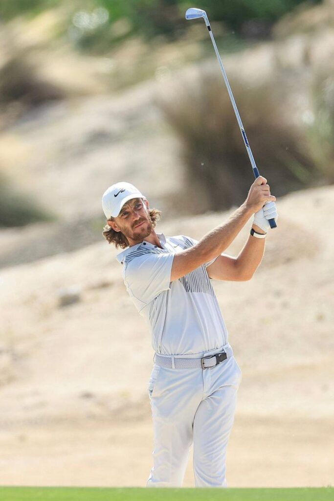 a man swinging a golf club on top of a green field