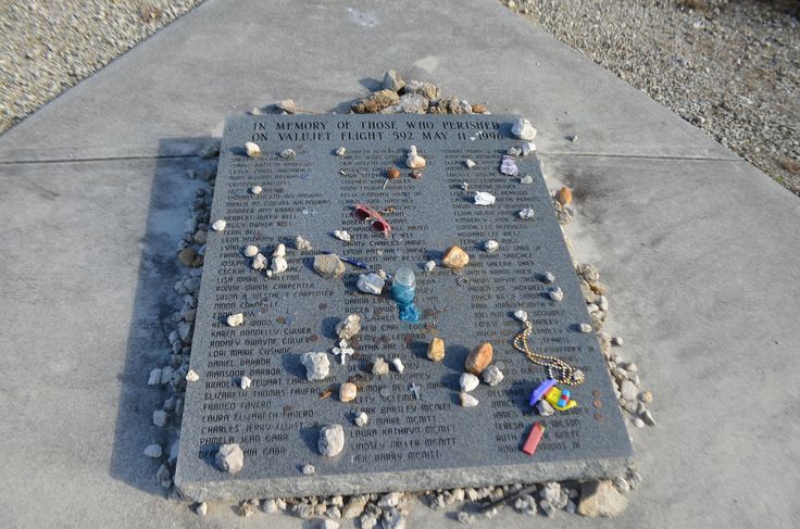 there is a memorial on the sidewalk with rocks and other things around it that are scattered about