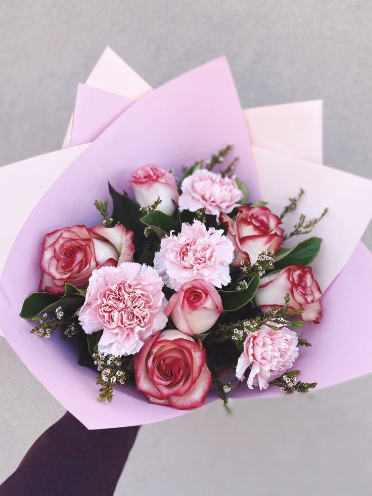 a bouquet of pink and white flowers in someone's hand