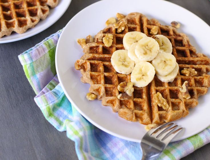 two white plates topped with waffles and bananas