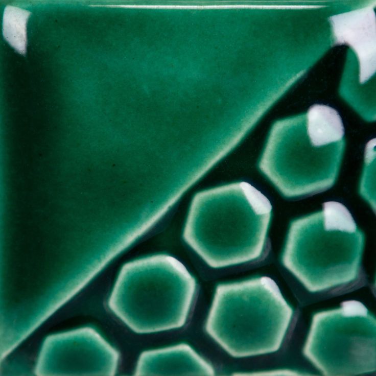 a green and white ceramic object with hexagonal designs on it's sides