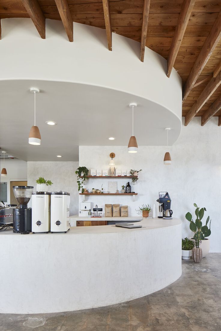 the interior of a restaurant with white walls and wood ceilinging, large circular counter