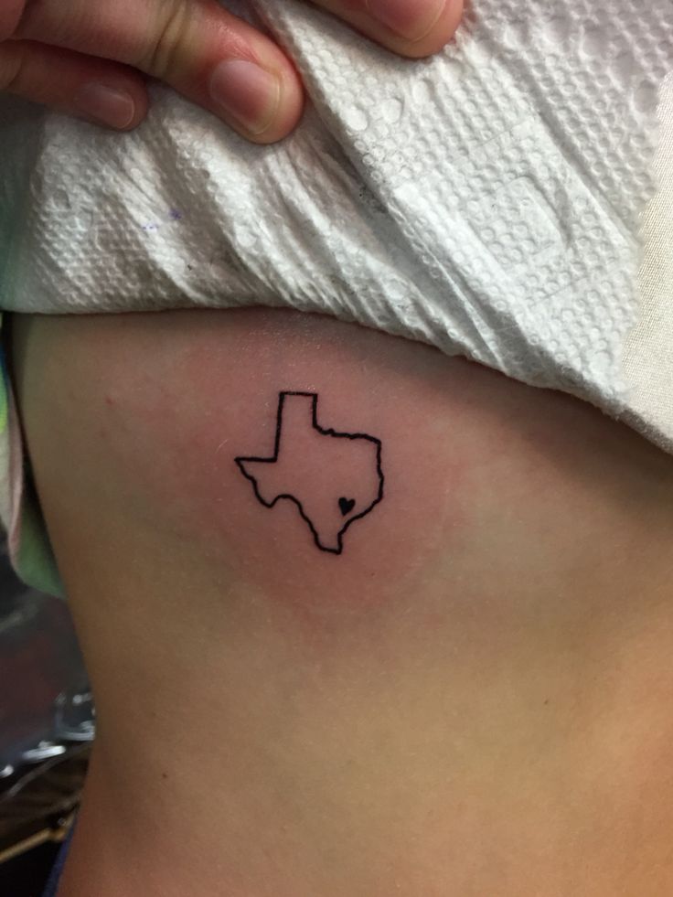 a woman's stomach with a small texas tattoo on her left side ribcage