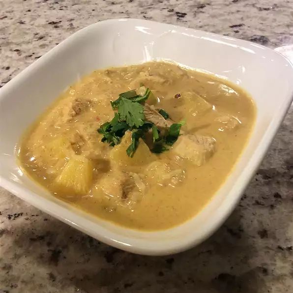 a white bowl filled with soup on top of a counter next to a knife and fork