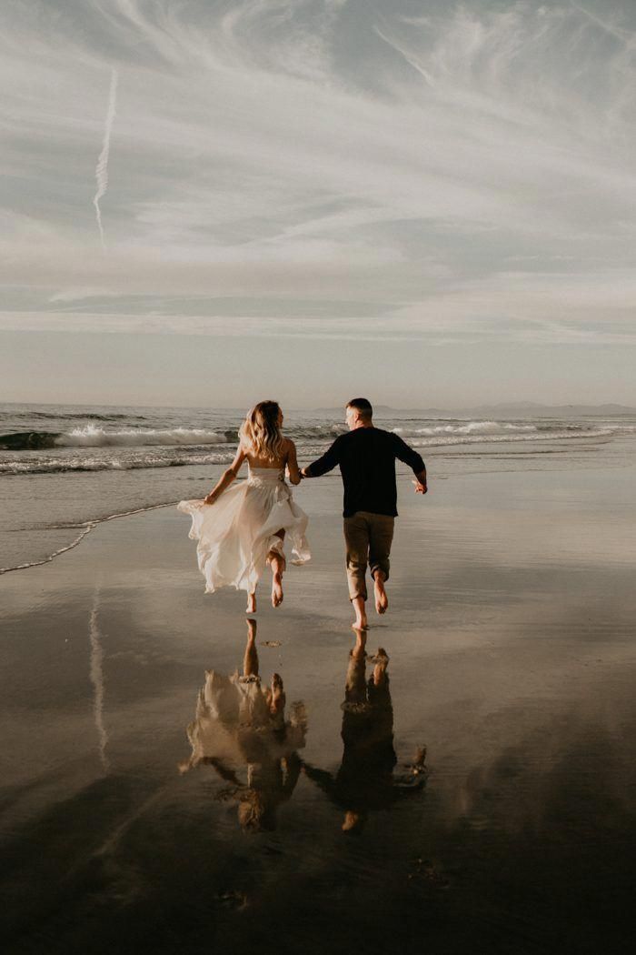 a couple running on the beach holding hands