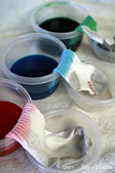 three plastic containers filled with different colored liquids and toothbrushes on a towel