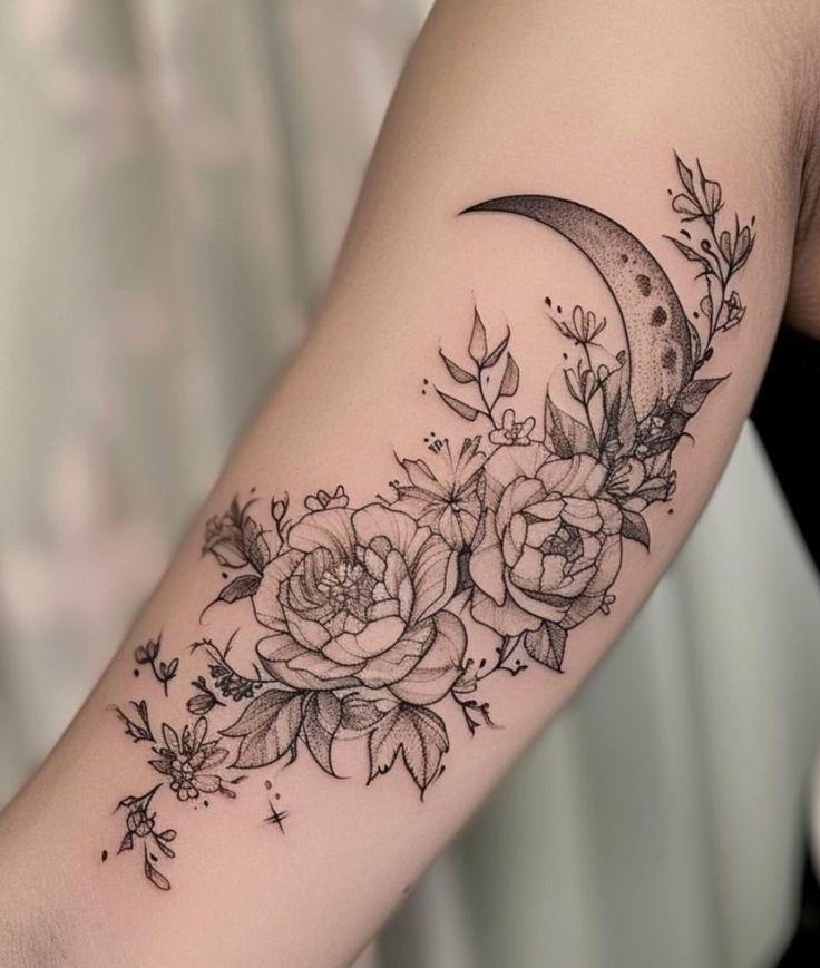 a woman's arm with flowers and a crescent tattoo