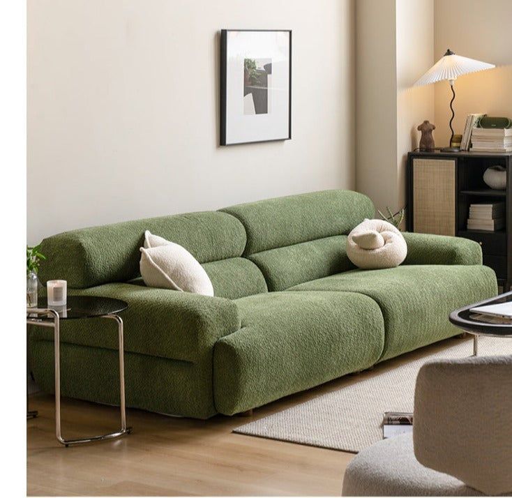 a living room with a green couch and white pillows on the back of it's seat