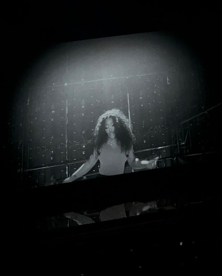 a black and white photo of a woman on a stage with her hair blowing in the wind