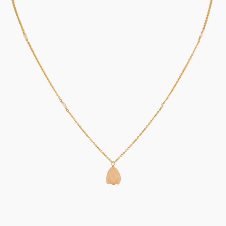 a gold necklace with a small leaf charm on the front and back of it's chain