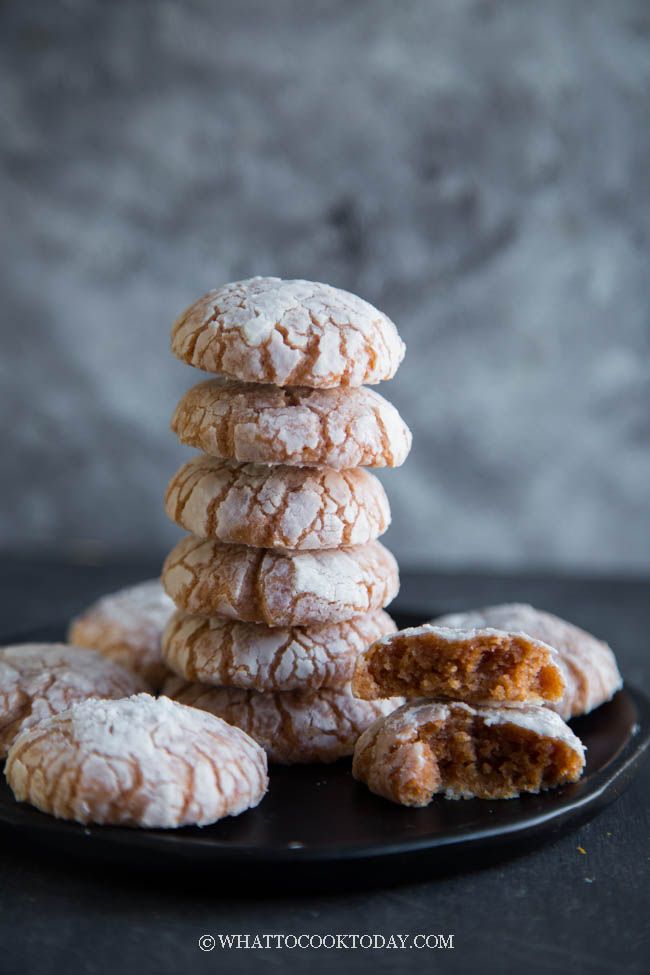 a stack of powdered sugar cookies sitting on top of a black plate