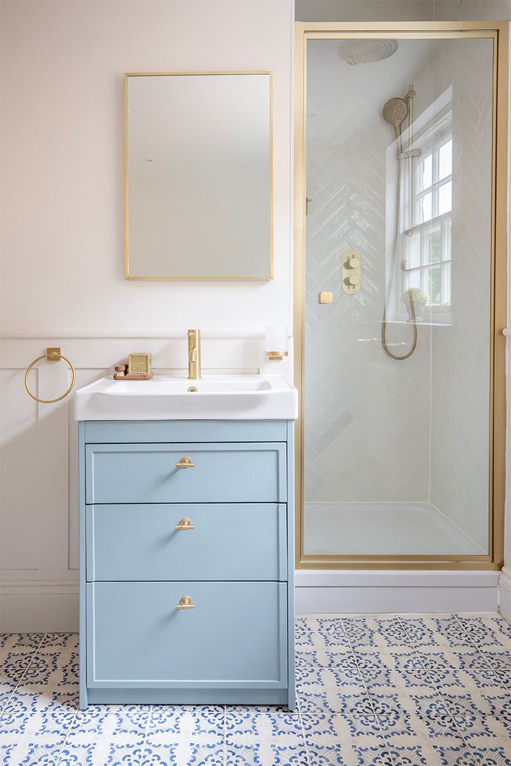 a bathroom with a blue cabinet, mirror and shower stall in the middle of it