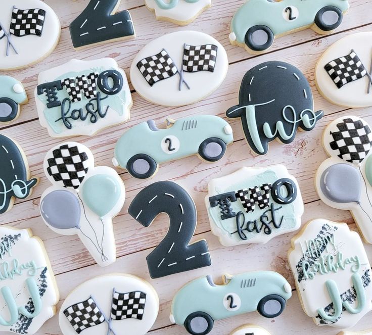 decorated cookies with numbers and race cars are arranged on a wooden table for a two year old birthday party