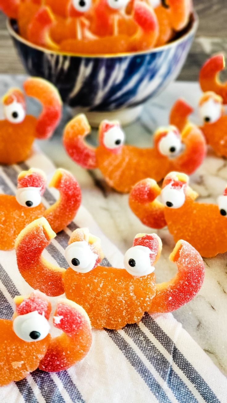 some orange candies with googly eyes are on a table next to a bowl