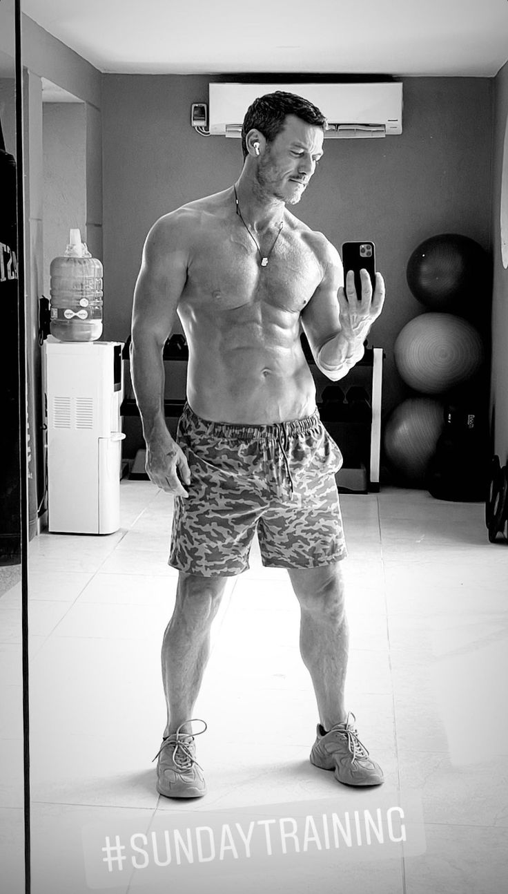 a shirtless man taking a selfie in front of a mirror with his cell phone