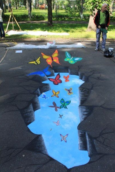 people are standing in the parking lot with chalk drawings on it and butterflies painted on the pavement