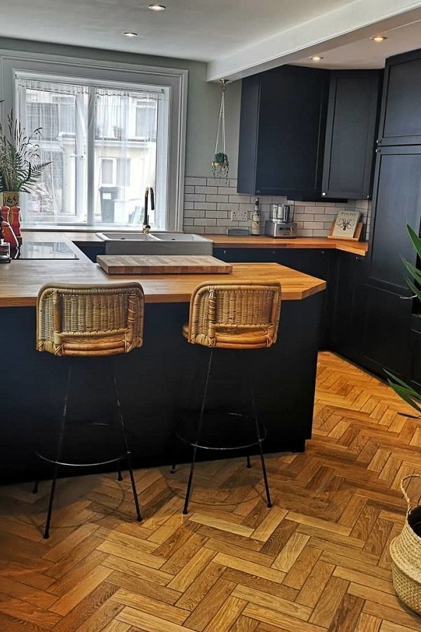 a kitchen with black cabinets and wooden floors