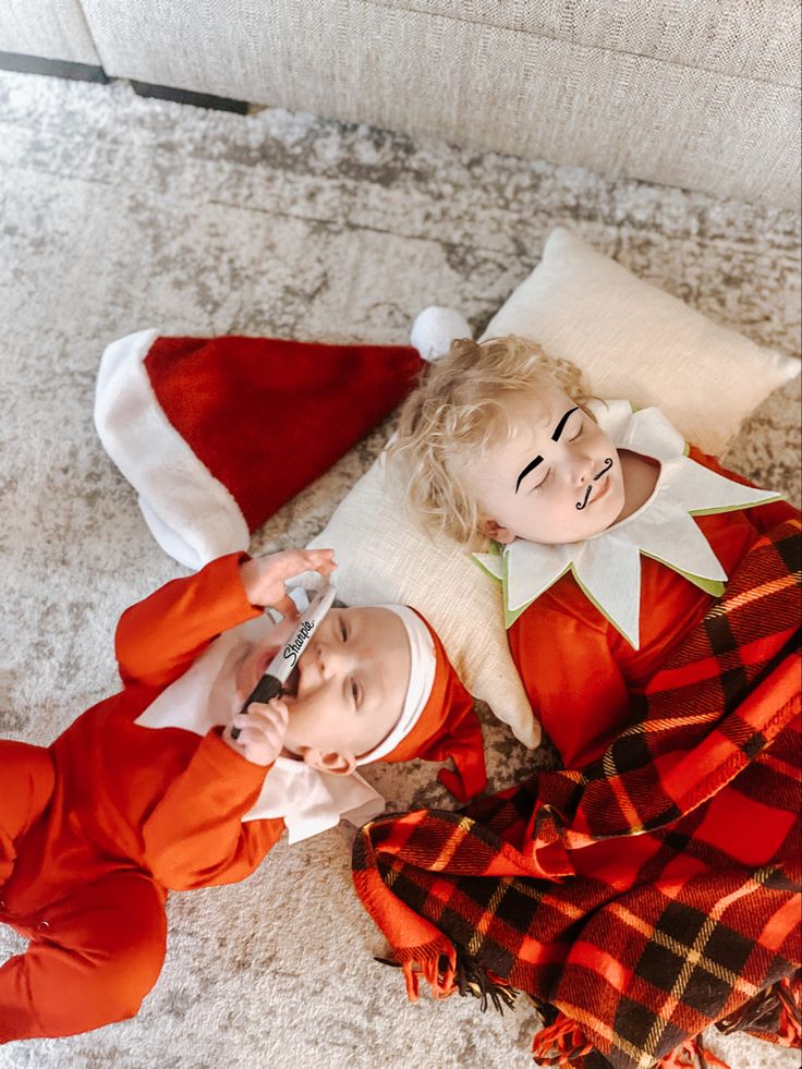 two dolls laying on the floor next to each other wearing red and white christmas outfits