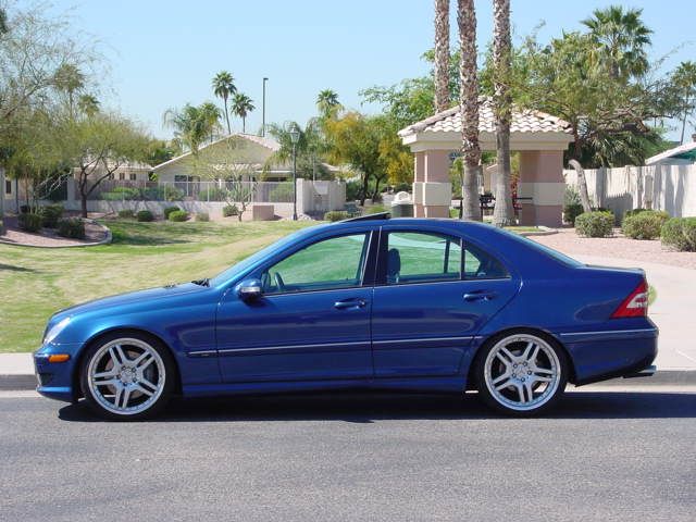 a blue car parked on the street in front of some palm trees and houses,