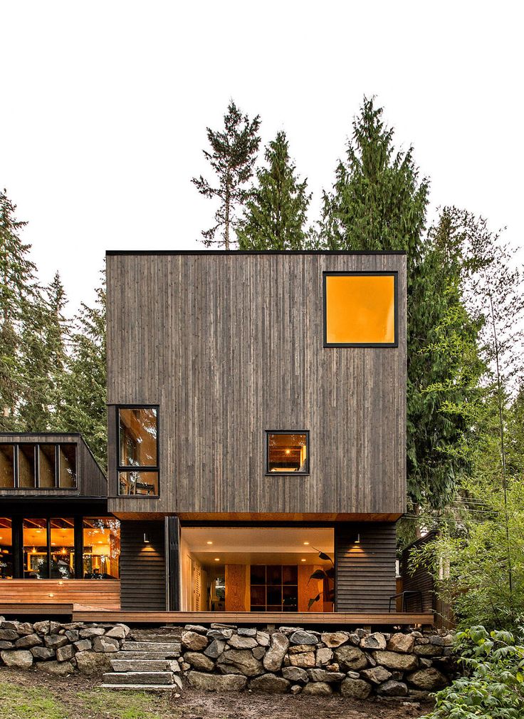 this modern house is built into the side of a wooded area with trees and rocks