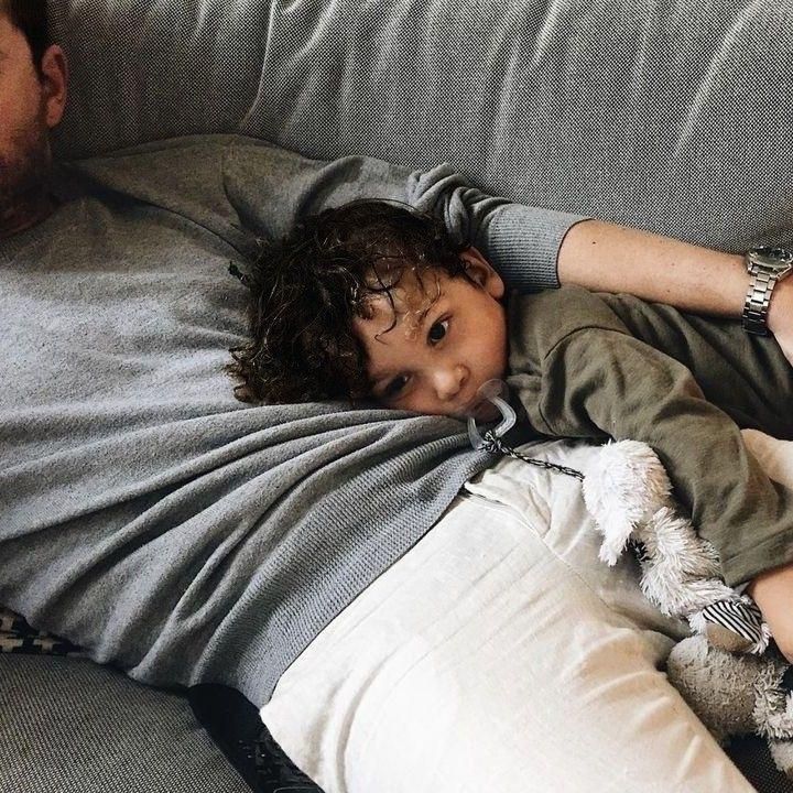 a man laying on top of a couch next to a little boy