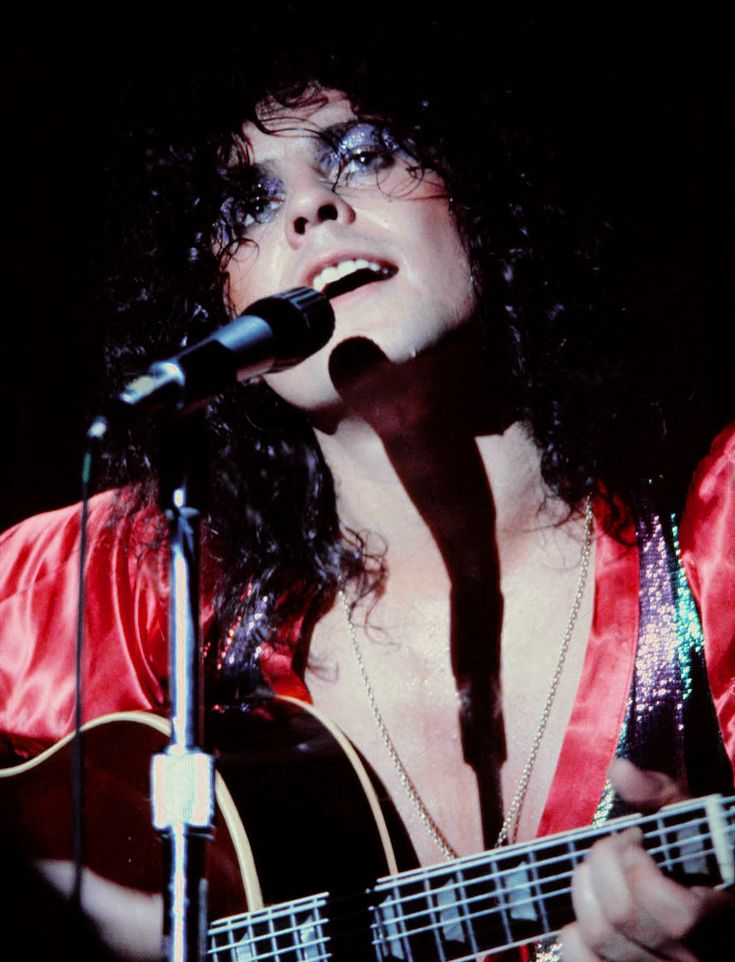 a woman singing into a microphone while holding a guitar