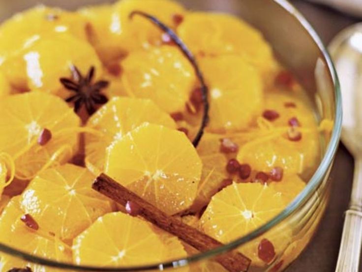 a glass bowl filled with sliced oranges next to a spoon