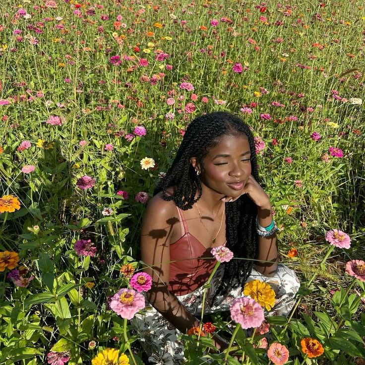 a woman sitting in the middle of a field of flowers