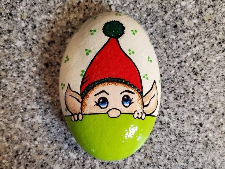 a painted rock with an elf's face on it, sitting on a granite surface