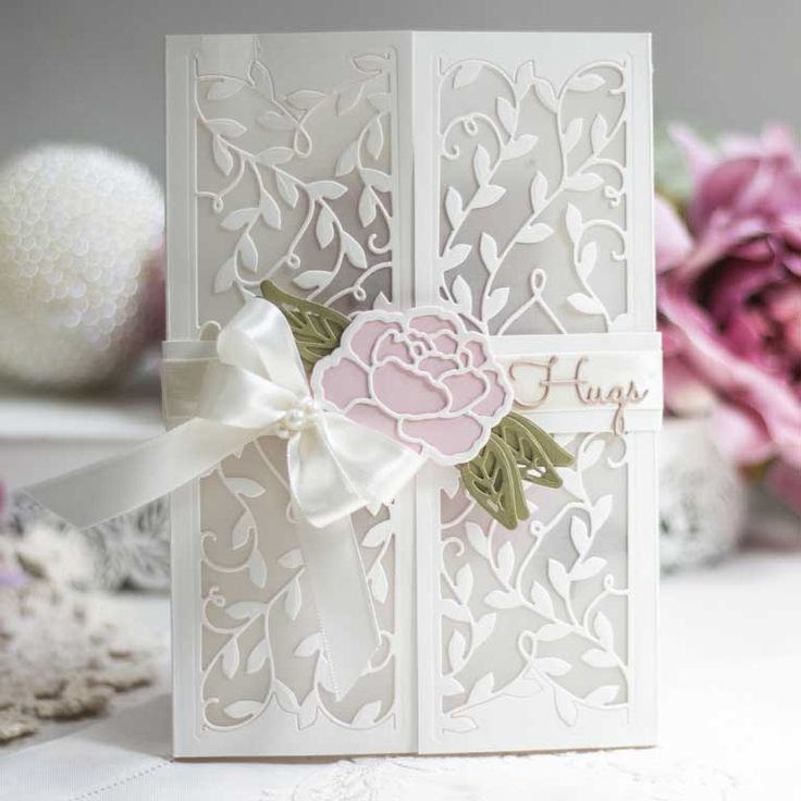 a close up of a card on a table with some flowers in the back ground