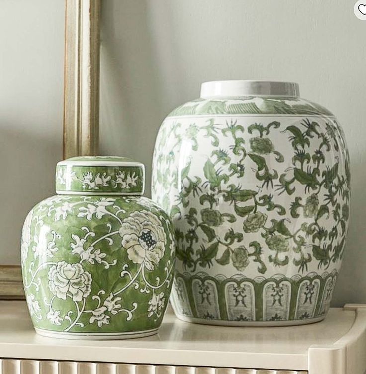 two green and white vases sitting on top of a shelf next to a mirror