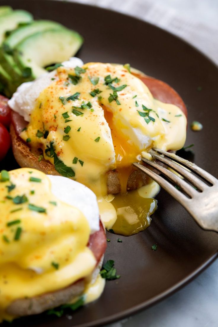 a plate with eggs, tomatoes and cucumbers on it next to a fork