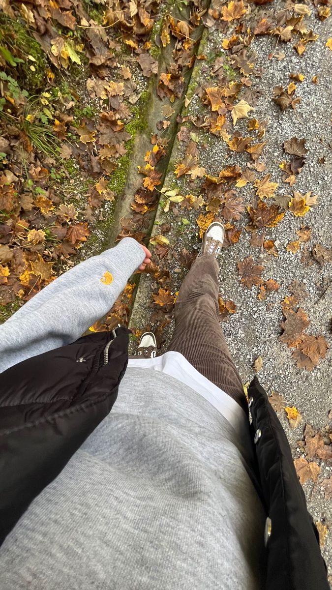 the legs and feet of a person who is standing in front of leaves on the ground