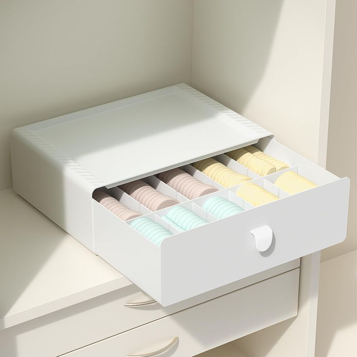 an open drawer with macaroons in it on top of a white countertop