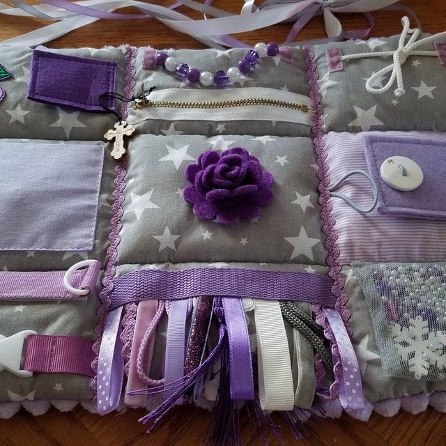 a close up of a bag on a wooden floor with ribbons and buttons attached to it