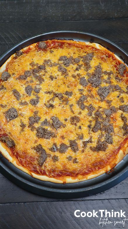 a pizza sitting on top of a metal pan covered in cheese and meat toppings