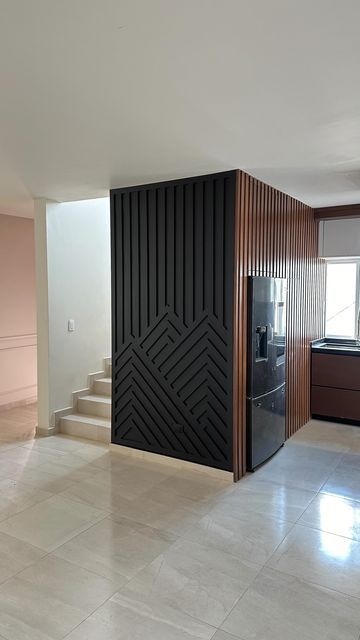 an empty room with a black door and white tile flooring on the ground, next to a staircase