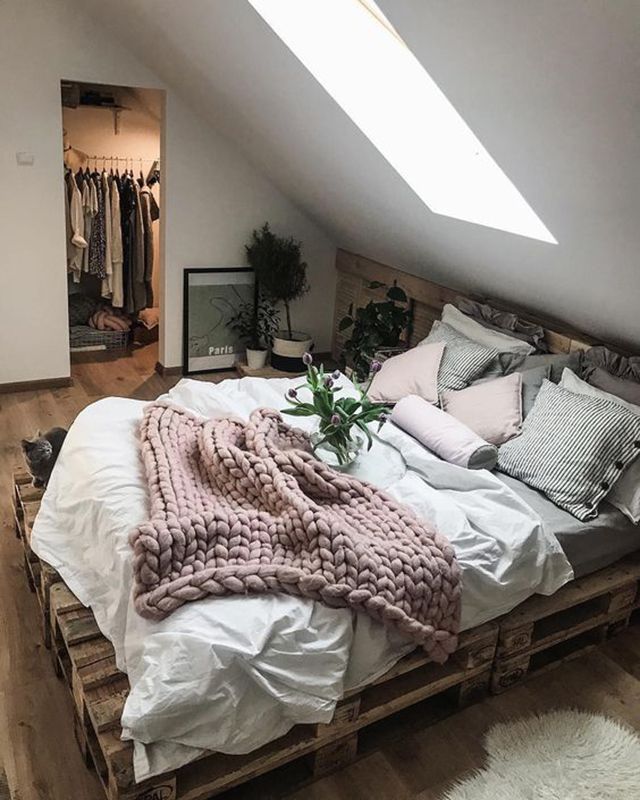 a bed made up with blankets and pillows on top of it in a loft space