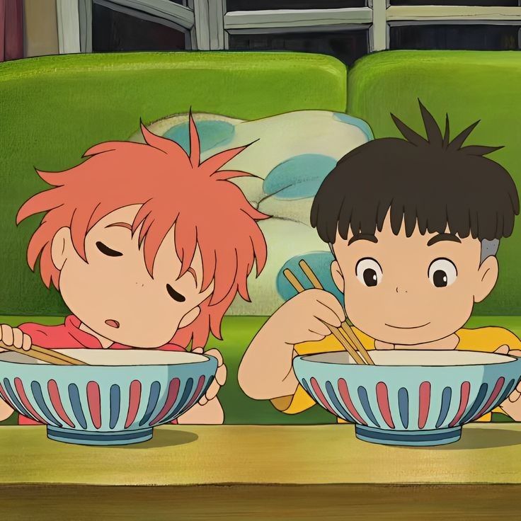 two young children sitting on a couch eating cereal from bowls with chopsticks in front of them