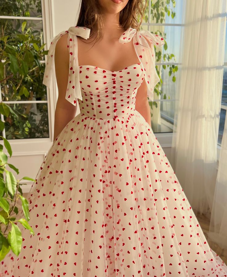 Introducing the "Bouquet of Hearts Gown" – a truly unique and enchanting piece perfect for romantic occasions. This stunning dress features eye-catching red velvet fluttering hearts on soft tulle fabric, a romantic sweetheart neckline, and a draped bodice. The A-line silhouette is complemented by a cinched waist, double bow straps, and a fully gathered skirt. Embrace the magic of love and style with this memorable ensemble. Heart Corset Dress, Love Bonito Dresses, Romantic Red Dress, Red Tulle Dress With Sweetheart Neckline, Cute Valentines Dresses, Red Organza Dress With Sweetheart Neckline, Red Sweetheart Neckline Dress For Valentine's Day, Heart Print Dress With Sweetheart Neckline, Fitted Dress With Sweetheart Neckline For Valentine's Day