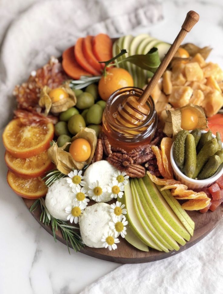 a platter filled with fruit, nuts and crackers on top of a marble table